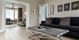 Un salon moderne avec un canapé, une table basse et un sol en revêtement stratifié imitant le bois naturel.