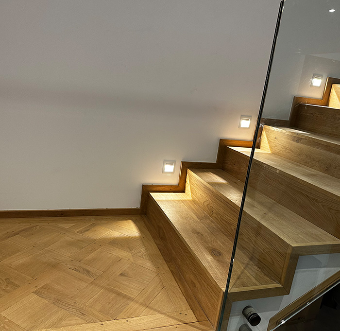 Escalier en bois élégant, flanqué d'une paroi en verre, offrant une vue dégagée et une touche contemporaine.