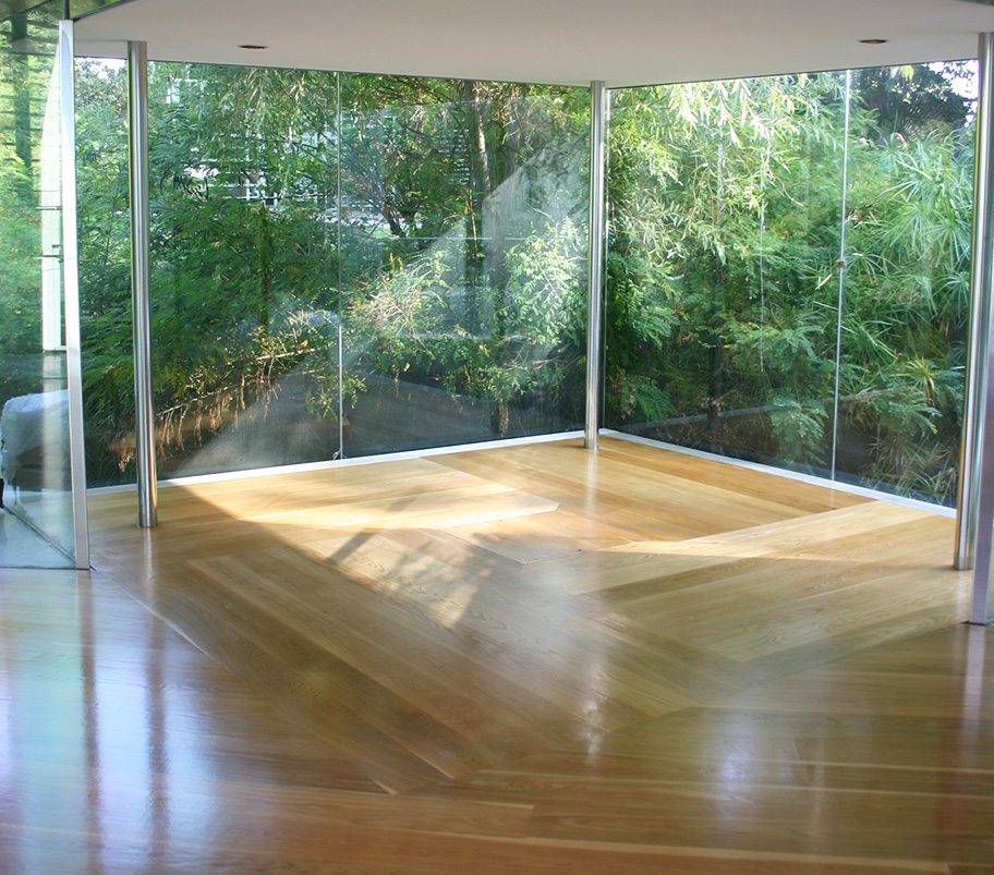 Salle spacieuse avec un parquet en bois et des parois en verre éclairées, créant une atmosphère lumineuse et ouverte.