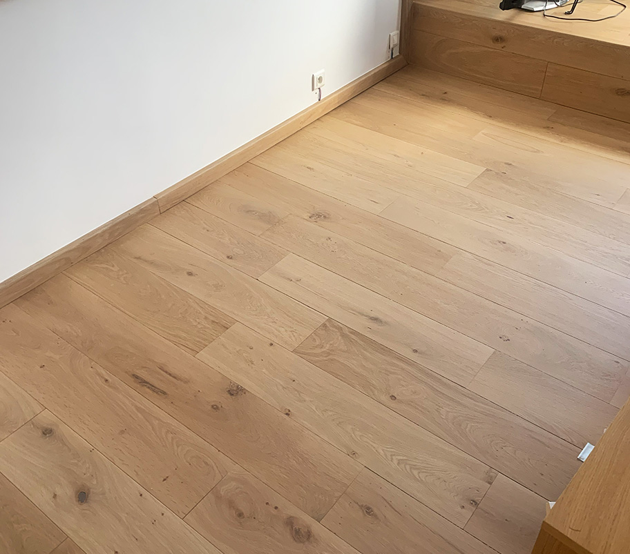 Un couloir avec un sol en parquet et une marche en bois, créant une ambiance chaleureuse et moderne.