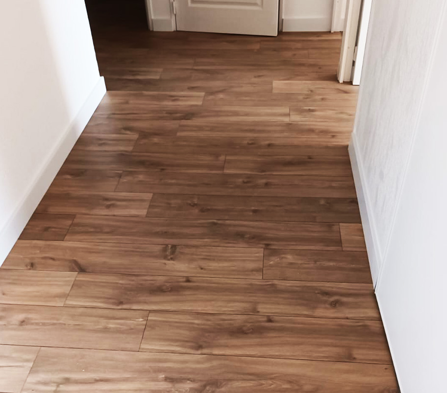 Couloir avec un parquet en bois et une porte, évoquant une atmosphère confortable et élégante.