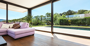 Ambiance salon chaleureux avec parquet en bois et vue sur le jardin et la piscine